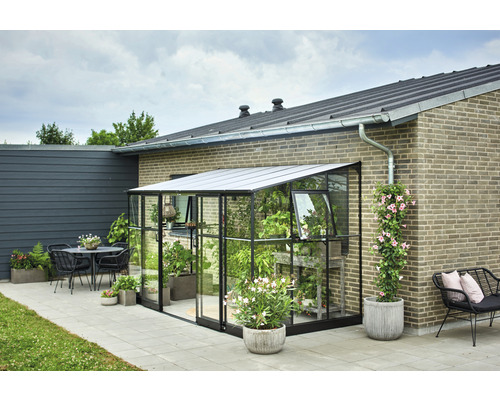 Gewächshaus aus Glas mit Pflanzen neben einem Haus und einer Terrasse