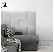Wohnzimmer mit grauem Sofa, Kissen und gepolsterten Wandpaneelen für eine stilvolle Inneneinrichtung.