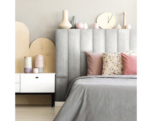 Schlafzimmer mit gepolstertem Kopfteil, Bettwäsche und dekorativen Elementen.