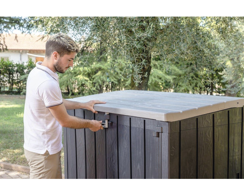 Mann öffnet eine Gartentruhe mit Deckel im Freien