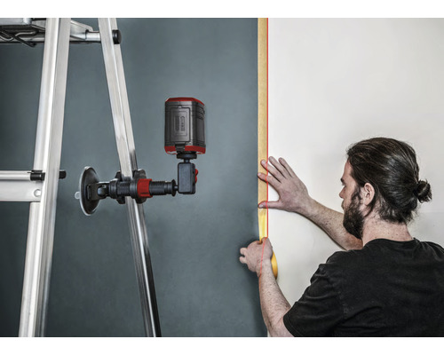 Anwender mit Linienlaser beim Ausrichten an Wand mit Leiter