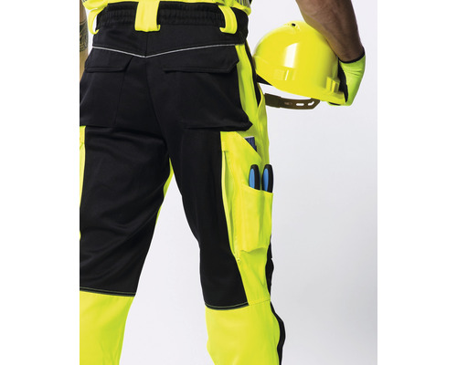 Gelb-schwarze Arbeitshose mit Taschen und einer Person, die einen Schutzhelm hält