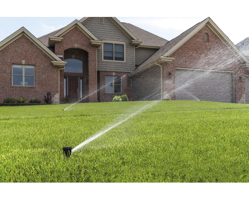 Rasenbewässerung vor einem Wohnhaus mit Rasensprengern