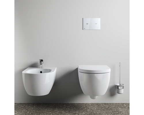 Wandhängendes Bidet neben einer wandhängenden Toilette mit Spülknopf und Toilettenbürste