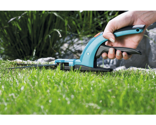 Hand hält Grasschere beim Grasschneiden