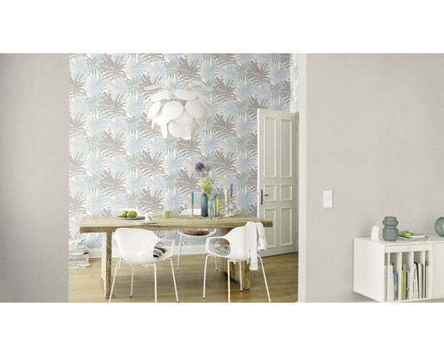 Wohnraum mit Esstisch, Stühlen, Pendelleuchte und einer Tapete mit Blattmuster