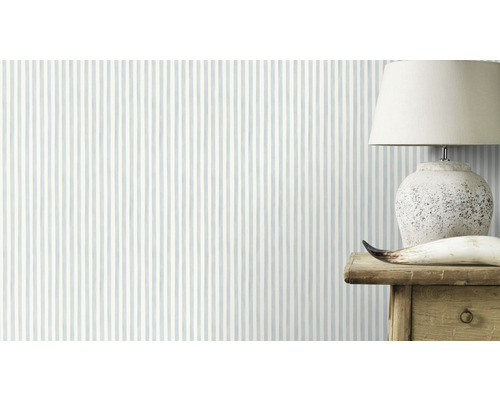 Tapete mit Streifenmuster im Raum, darauf eine Lampe auf einem Holztisch