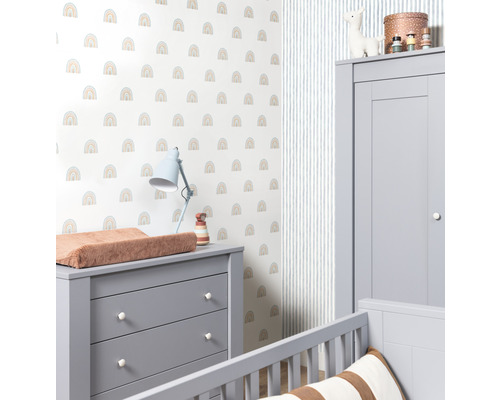 Ein Kinderzimmer mit einer Wickelkommode, einem Kleiderschrank und einer Wand mit Regenbogenmuster.