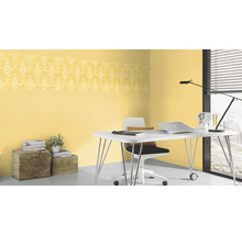 Büro mit gelber gemusterter Bordüren Tapete, Schreibtisch, Stuhl und Accessoires.