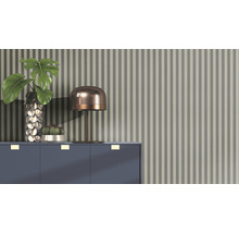 Dekoratives Arrangement mit Tischlampe, Vase, Pflanze und Kaktus auf einem Schrank vor einer gestreiften Tapete.