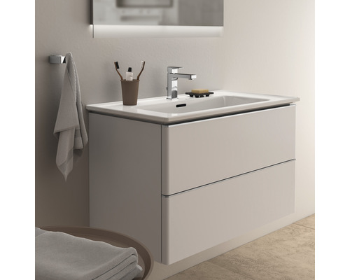 Waschbeckenunterschrank mit zwei Schubladen, Armatur und Spiegel in einem hellen Badezimmer.