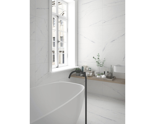 Helles Badezimmer mit freistehender Badewanne, Armatur und Wandfliesen in Marmoroptik