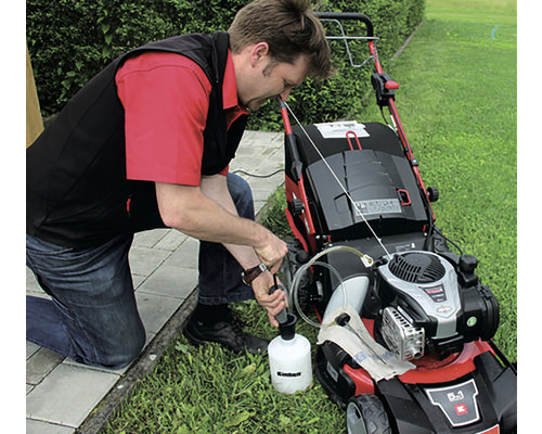 Mann füllt Öl in einen Rasenmäher um