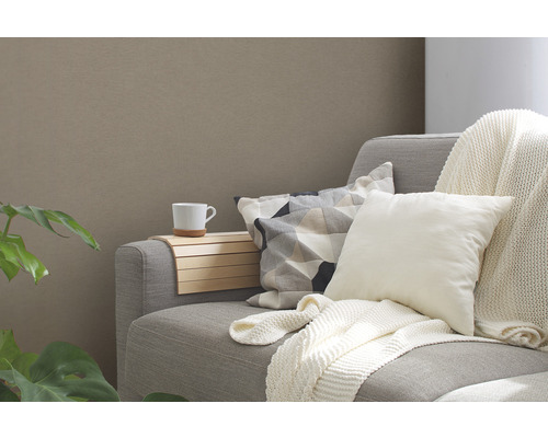 Graues Sofa mit Kissen, einer Tasse und einer Holzablage.
