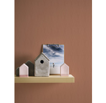 Dekorative Vogelhäuser aus Beton und Holz auf einem Regal mit einer Fotografie eines Strandes.