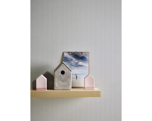 Dekorative Szene mit Hausfiguren, einer Klemme und einer Holzablage vor einer Tapete.