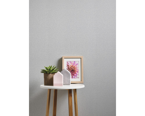 Nahaufnahme einer silberfarbenen Tapete mit Tisch, Pflanze, Dekohäusern und einem Bilderrahmen