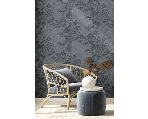 Wohnszene mit blaugrauer Tapete mit Baum-Muster, Sessel und Hocker