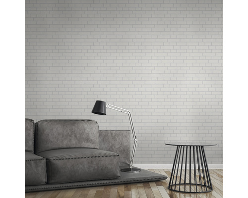 Wohnzimmer mit Sofa, Stehlampe und Beistelltisch vor einer Wand mit Backsteintapete.