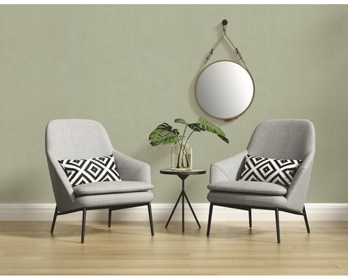 Helle Inneneinrichtung mit zwei grauen Sesseln, einem Beistelltisch und einem runden Spiegel an der Wand