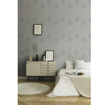 Schlafzimmer mit grauer Tapete, Kommode und Bett.