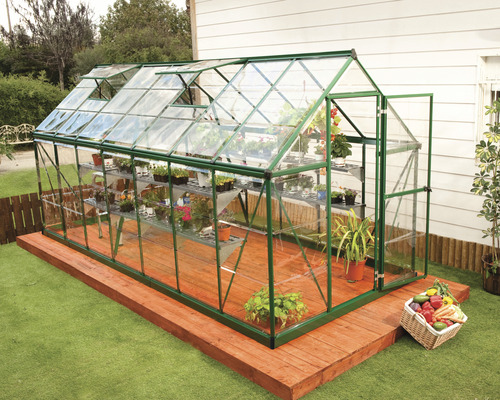 Gewächshaus mit Regalen, Pflanzen und geöffneten Fenstern auf einer Holzterrasse