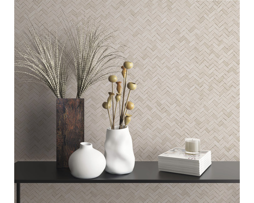 Dekorative Szene mit Vasen, Zierpflanzen, Kerze und Büchern auf einem Regal vor einer Wand mit Fischgrätenmuster.