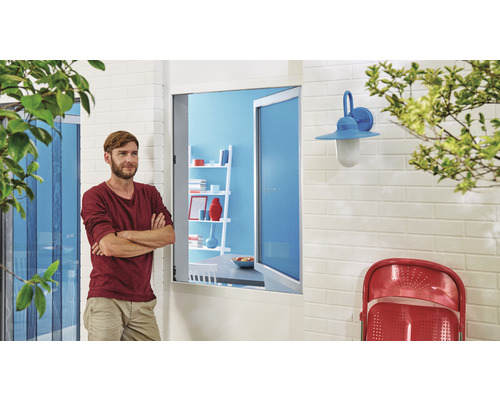 Mann steht vor einer geöffneten Tür mit Insektenschutzgitter und Blick auf eine Terrasse mit Lampe und Stuhl