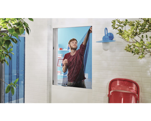 Mann befestigt Insektenschutzgitter an einem Fenster im Außenbereich.