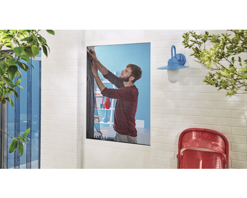 Mann befestigt Insektenschutzgitter an einem Fenster