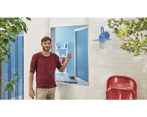 Mann zeigt auf ein Insektenschutzgitter für Fenster in einem Wohnbereich