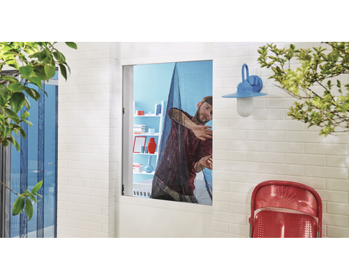 Mann montiert ein Fliegengitter an einem Fenster für Insektenschutz.