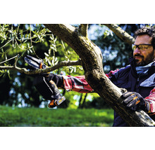 Eine Person benutzt eine Akku-Kettensäge zum Beschneiden eines Astes.