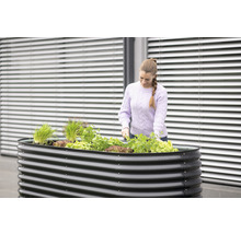 Hochbeet aus Metall mit Pflanzen und Frau bei der Gartenarbeit
