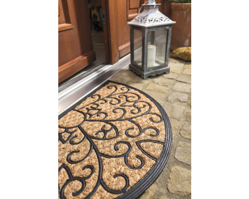 Halbrunde Fußmatte aus Kokosfaser mit floralem Muster vor einer Haustür