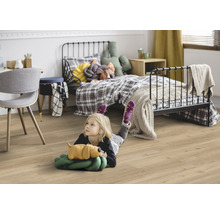 Kind liegt auf einem Laminatboden in einem Kinderzimmer mit Bett und Schreibtisch