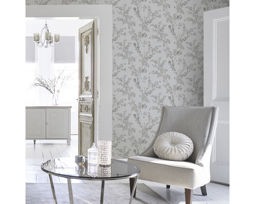 Heller Wohnraum mit floral gemusterter Tapete, Sessel, Tisch und Dekoration