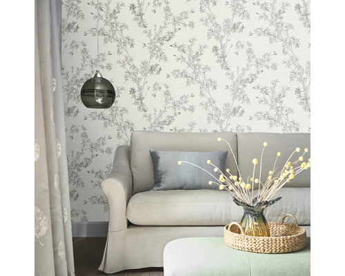 Wohnzimmer mit Couch, Lampe und floraler Tapete