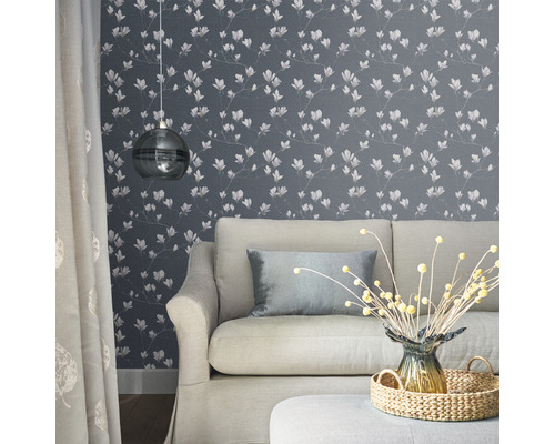 Wohnzimmer mit Couch, Lampe und floraler Tapete