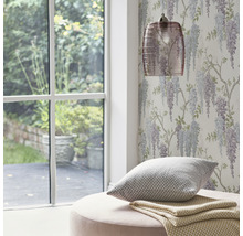 Zimmer mit Fenster, floraler Tapete, Lampe, Kissen und Hocker