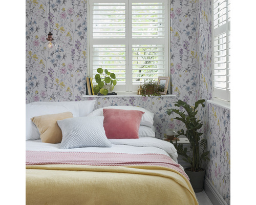 Schlafzimmer mit floraler Tapete, Bett, Kissen und Fenster mit Fensterläden