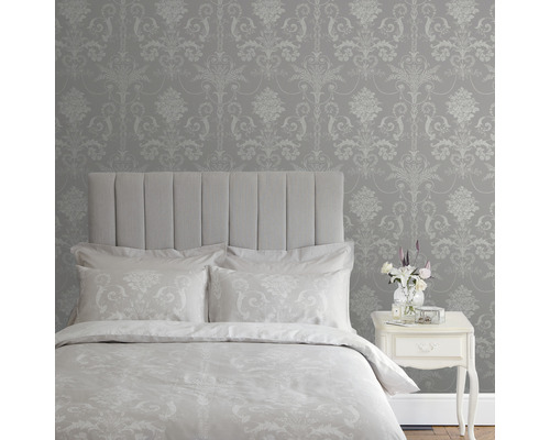 Schlafzimmer mit Bett, Nachttisch und gemusterter Tapete im Damaststil