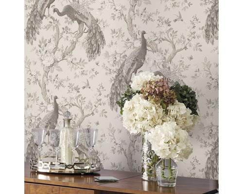 Innenraum mit gemusterter Tapete mit Pfauen, Blumen, Getränke-Set auf einem Tisch und Blumen in Vasen.