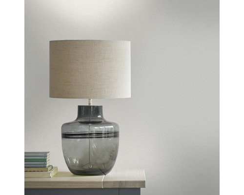 Tischleuchte mit Stoffschirm und Glasfuß auf einem Tisch