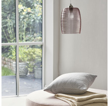Szene mit Glaspendelleuchte, Kissen und Decke auf einem Hocker in der Nähe eines Fensters