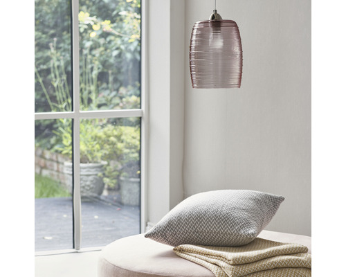 Szene mit Glaspendelleuchte, Kissen und Decke auf einem Hocker in der Nähe eines Fensters