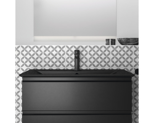 Waschtischunterschrank mit Becken, Armatur und Spiegel vor gemusterter Wand