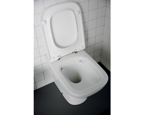 Weiße Standtoilette mit offenem Toilettendeckel vor weißen Fliesen