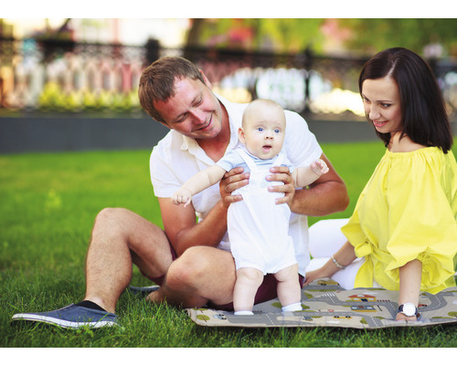 Familie mit Baby auf einer Spielmatte im Freien.