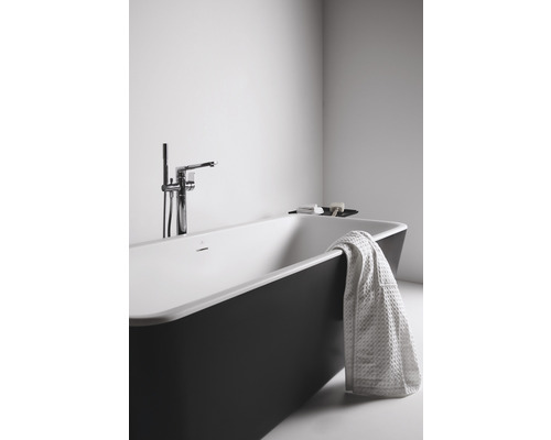 Freistehende Badewanne mit Handtuch und Armatur im Badezimmer.